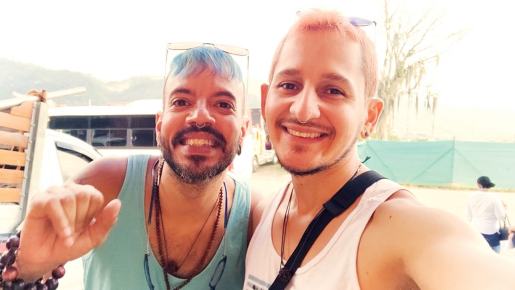 This is a photo of us, the Queer Nomad Boys, Andy and Feli. In the background there is the a town near by the city of Medellin in Colombia. 